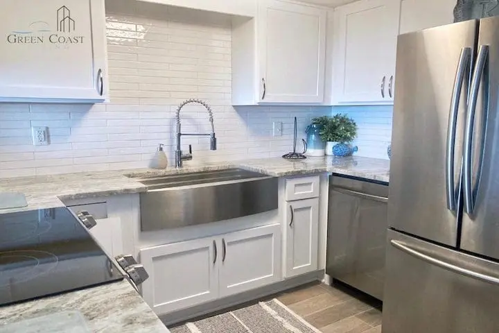 A remodeled modern white kitchen with stainless steel appliances and hardware. Located in a luxury condominium in Orange Beach, Alabama.