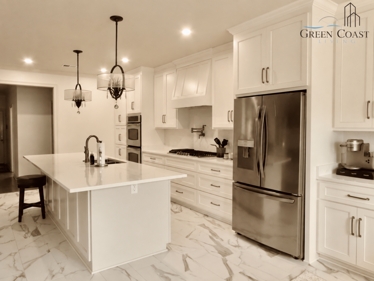 Finished kitchen remodel in Daphne with white cabinets, a center island, stainless steel appliances, and marble-look tile flooring.