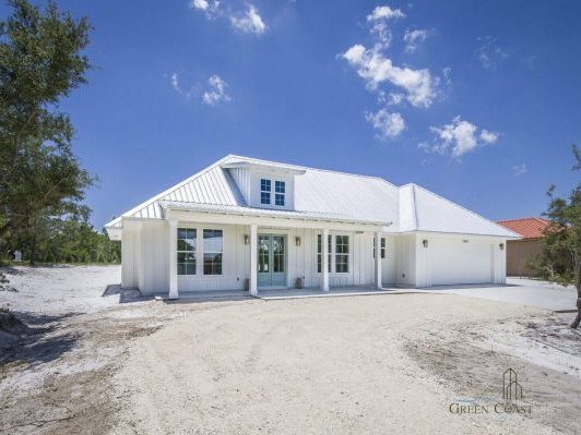 White custom home on Ono Island with a metal roof, covered front porch, and attached garage.