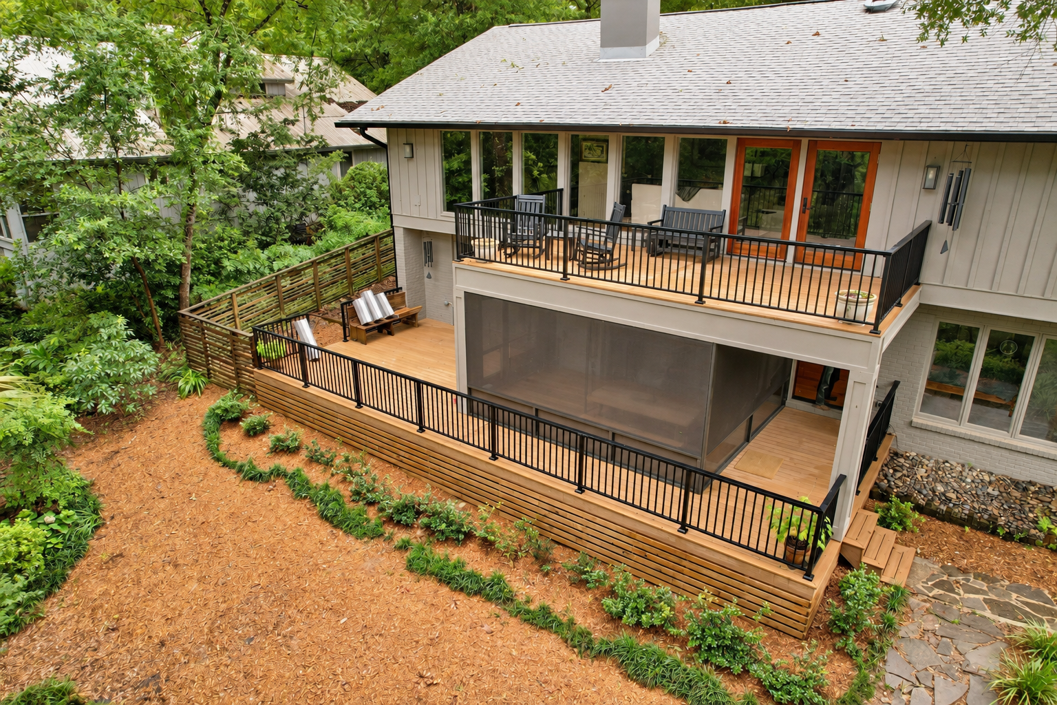 Renovated Fairhope home featuring two levels of wood decking, black metal railings, a screened porch, and updated exterior finishes.